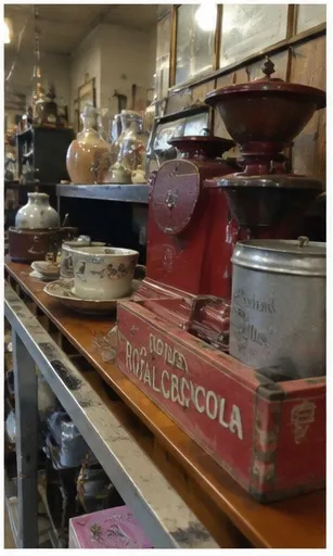 Red antique coffee grinder and Royal Crown Cola crate on a shelf